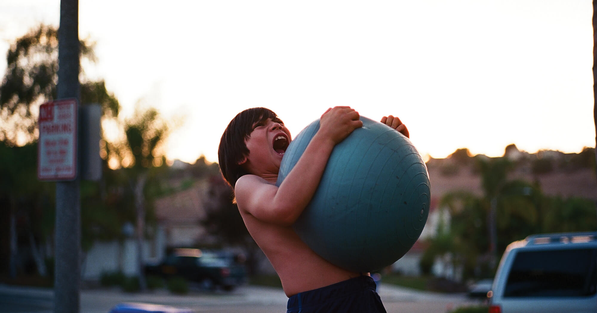 A child yelling while lifting a ball