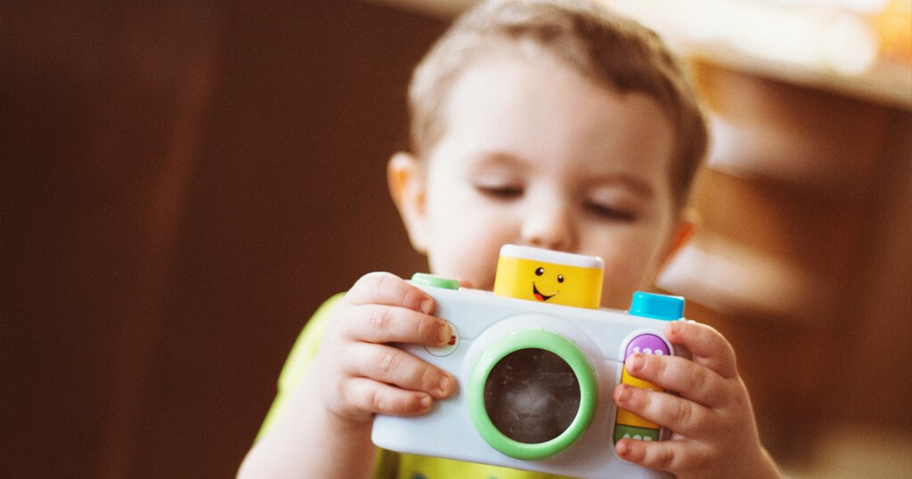 Little child playing with a toy camera