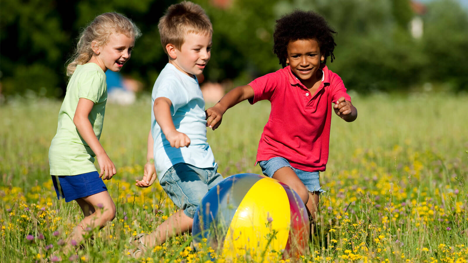 Three kids playing with a beach ball together
