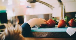 child stealing a strawberry